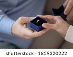 Declaration of love. Close up of loving male holding small box with diamond ring in hand presenting it to beloved young female, asking to marry him, making wedding proposal on engagement betrothal day