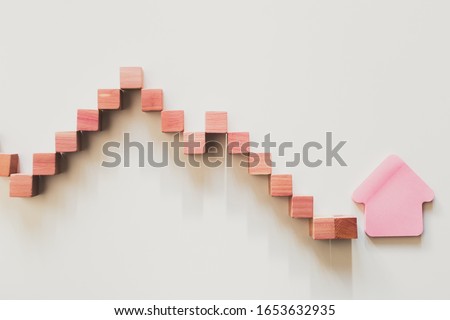 Declining graphic curve made with wooden boxes with house shape on the end. House budgeting
