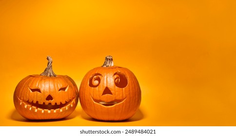 Decor of carved Halloween pumpkins as Jack-o'-lantern over orange background with copy space - Powered by Shutterstock