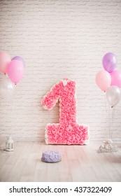 Decor First Birthday. The Number 1 In The Form Of A Pinata. Pink 1st Birthday Pinata On A Background Of A Brick Wall