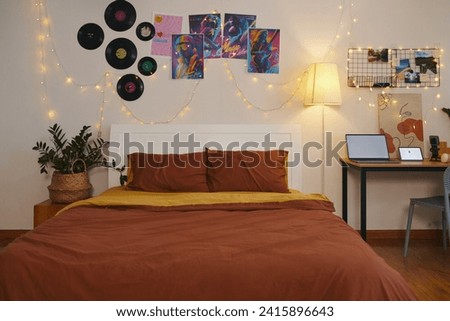 Decorated bedroom of teenager with string lights, placards and vinyl records on walls