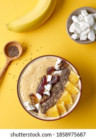 Decorated Breakfast Smoothie Bowl Of Banana And Orange On Yellow Background, Top View