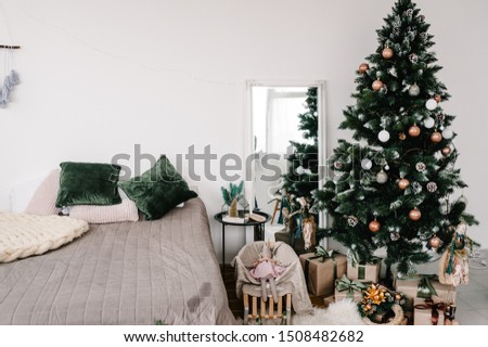 Decorated Christmas interior. Christmas tree with gifts boxes in a white room. Fir-tree decorated with garlands. Decor. Happy New Year and Merry Christmas. The concept of winter holiday.