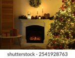 Decorated Christmas tree near fireplace in room. Festive interior design