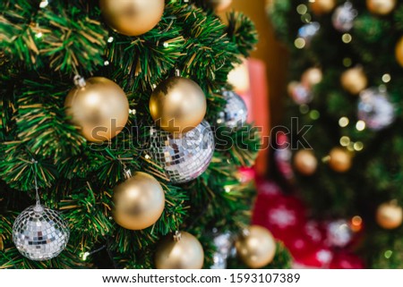 Decorated Christmas tree on blurred background. Close-up mirror ball and gold balls ornament of Christmas tree decoration in sparkling and fairy background.
