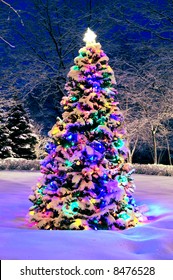 Decorated Christmas Tree Outside With Lights Covered With Snow