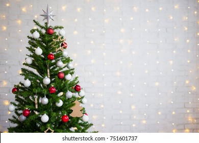 Decorated Christmas Tree Over White Brick Wall With Shiny Lights