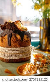 Pan de Pascua decorado con glaseado de chocolate, rodajas de naranja y migas de esponja en un plato.