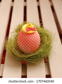 Decorated Easter Egg In Grass Nest With Checkered Pattern In A Yellow Hat 