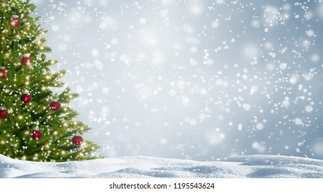 decorated fir tree in snowy landscape, beautiful christmas tree with red balls on abstract winter background with advertising space, white snowflakes in front of the silver sky