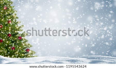 decorated fir tree in snowy landscape, beautiful christmas tree with red balls on abstract winter background with advertising space, white snowflakes in front of the silver sky