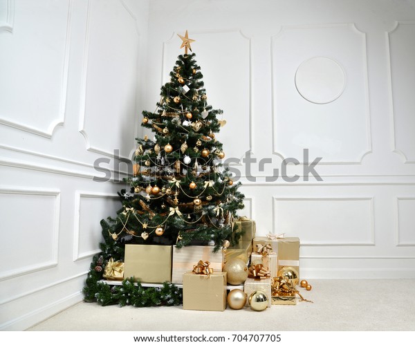 Decorated gold Christmas tree with golder\
patchwork ornament artificial star hearts presents for new year in\
rich house on white\
background