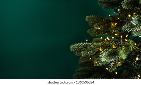 Decorated with lights Christmas tree on dark green background. Merry Christmas and Happy Holidays greeting card, frame, banner. New Year. Noel. Winter holiday theme. 