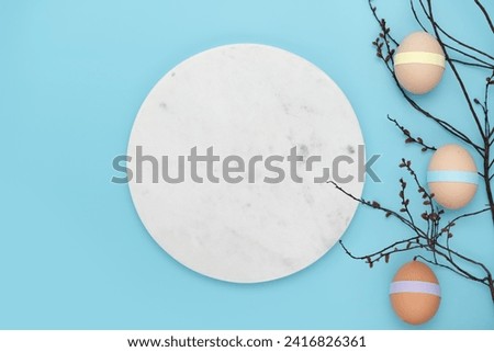 Decorated with paper eggs on a burgeoning branch with marble podium. Fun empty Easter background. Copy space simple pastel rustic background for traditional Easter holiday card