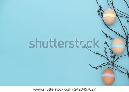 Decorated with paper eggs on a burgeoning branch. Fun empty Easter background. Copy space simple pastel rustic background for traditional Easter holiday card
