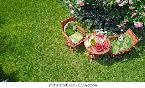 Decorated Table With Bread, Strawberry And Fruits In Beautiful Summer Rose Garden, Aerial Top View Of Romantic Date Table Food Setting For Two From Above
