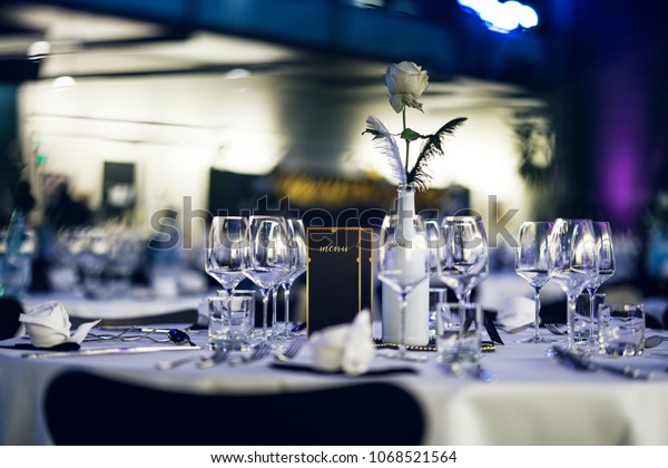 Decorated table on a gala dinner party with\
wine glasses and blurred out\
background
