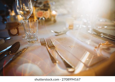 Decorated table in warm light, forks, glasses, and menu creating a festive and upscale dining experience