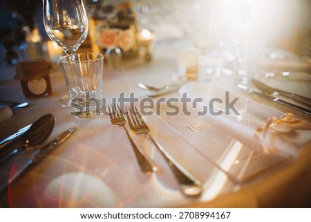 Decorated table in warm light, forks, glasses, and menu creating a festive and upscale dining experience