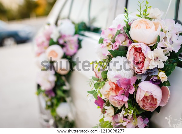 Decorated wedding car. Floral design concept\
applied to a wedding car. Light violet, soft pink and white roses\
bouquet hanging on a white car\'s\
doors.