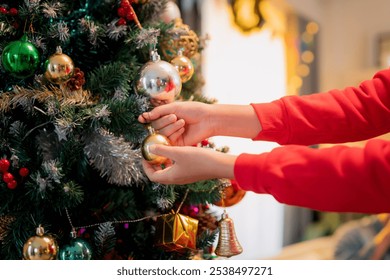 Decorating Christmas tree with colorful ornaments brings joy and festive spirit. hands carefully place golden bauble among vibrant decorations, creating warm holiday atmosphere. - Powered by Shutterstock