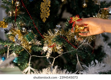 Decorating a Christmas tree to prepare for the Christmas and New Year festivities. - Shutterstock ID 2394545073