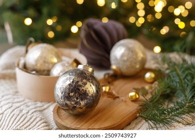 Decorating christmas tree with vintage golden baubles. Stylish Christmas ornaments in box on rustic table on background of christmas tree with lights. Merry Christmas - Powered by Shutterstock