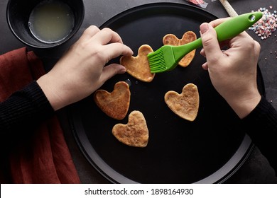 Decorating Cookies For Valentine's Day. A Woman Decorates A Heart-shaped Cookie. Cookies For Valentine's Day