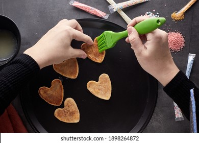 Decorating Cookies For Valentine's Day. A Woman Decorates A Heart-shaped Cookie. Cookies For Valentine's Day