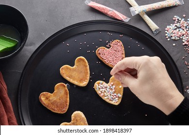 Decorating Cookies For Valentine's Day. A Woman Decorates A Heart-shaped Cookie. Cookies For Valentine's Day