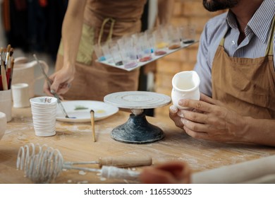 Decorating handiworks. Two creative skillful potters using color paints for decorating their handiworks