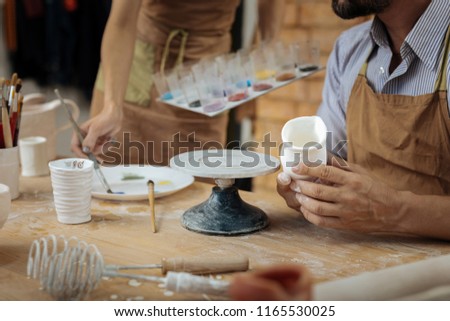 Decorating handiworks. Two creative skillful potters using color paints for decorating their handiworks