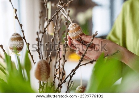 Decorating pussy willows branches with easter eggs.