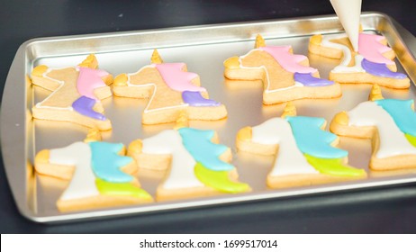 Decorating unicorn sugar cookies with multi-color royal icing.
