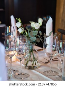 Decoration Arrangement Of Glasses, Flowers, Napkins, And Small Burning Candles For A Wedding Party. 