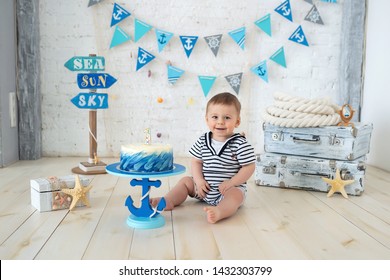 decoration for the boy's first birthday, smash the cake in a nautical marine style. stylized birthday ship photo shoot. Cheerful boy eats and break a cake with his hands on the first holiday