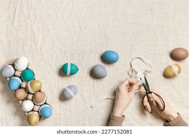 Decoration colored Easter eggs, prepare for Happy Easter celebration, woman decorating dyed chicken egg with tape lace on table linen background. Lifestyle aesthetic photo at home, diy holiday - Powered by Shutterstock