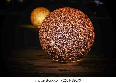 Decoration for garden deck. Light balls consisting of round shaped lamps made of plastic kept on a wooden floor. The image was taken in low light condition in outdoor setting.