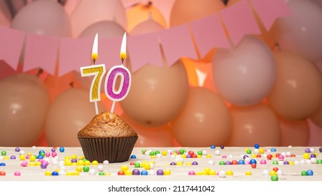Decorations with balloons and a happy birthday candle with the number 70 for a woman. Happy birthday greetings in pink flowers for seventy years for an adult woman, copy space. Muffin - Shutterstock ID 2117441042
