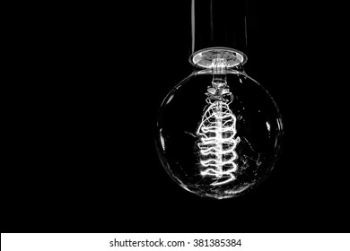 Decorative antique edison style light bulb on black background. Black and white - Powered by Shutterstock