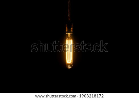 Decorative antique vintage style light bulb glowing in the dark. Creativity ideas concept.
