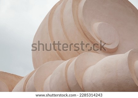 Decorative architecture detail in a spiral shape. Abstract gray and rose color concrete sculpture close-up background