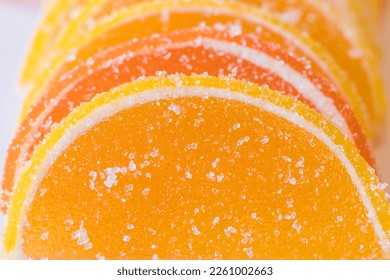 Decorative Background of yellow and orange marmalade candy in the shape of citrus fruits wedges. Jelly sweet candies. Food Texture. Beautiful marmalade lemon wedges white background.