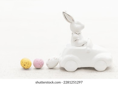 Decorative ceramic hare in a car and Easter eggs, close-up.