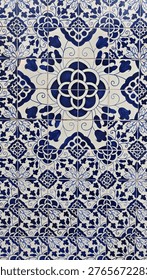 Decorative ceramic tile pattern featuring intricate blue and white floral designs arranged symmetrically on a wall, showcasing traditional craftsmanship and artistry