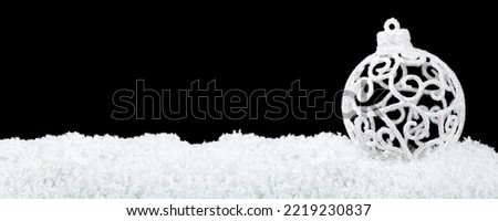 Decorative christmas ball on white snow isolated on a black background