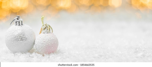 Decorative Christmas Balls Laying In A Snow With Yellow Lights Bokeh On The Background. Greeting Card For New Year Holidays Or Party With Copy Space.