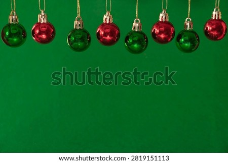 Decorative composition with several red and green Christmas balls suspended on a green out of focus background.