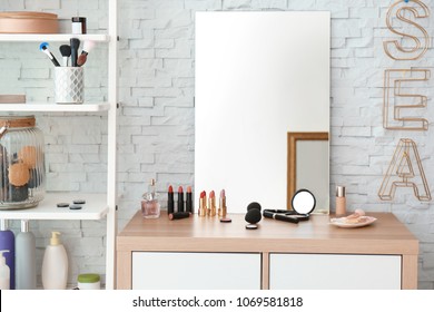 Decorative cosmetics and tools on dressing table near mirror in makeup room
