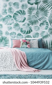 Decorative Cushions With Plain And Floral Prints On A Turquoise Bed By A Leaves Wallpaper In Bedroom Interior